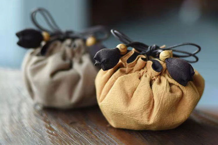 A light brown and dark brown mala beads pouches on a wodden table.