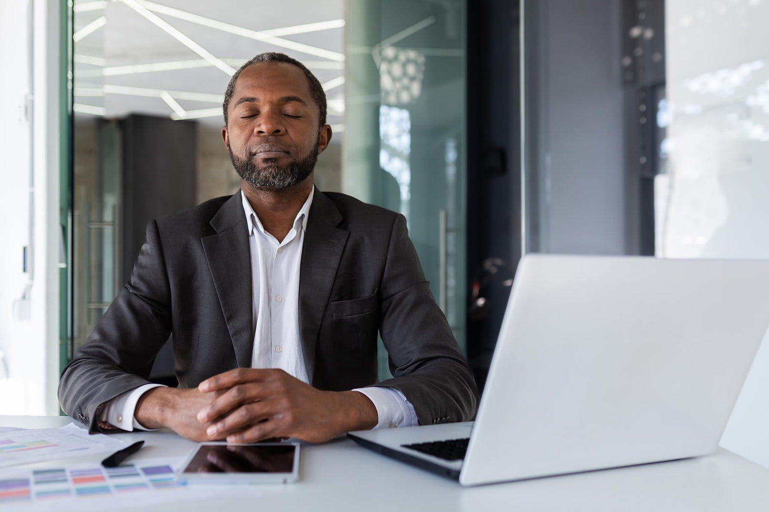 Man at work sitting quietly at his desk in mindful meditation.