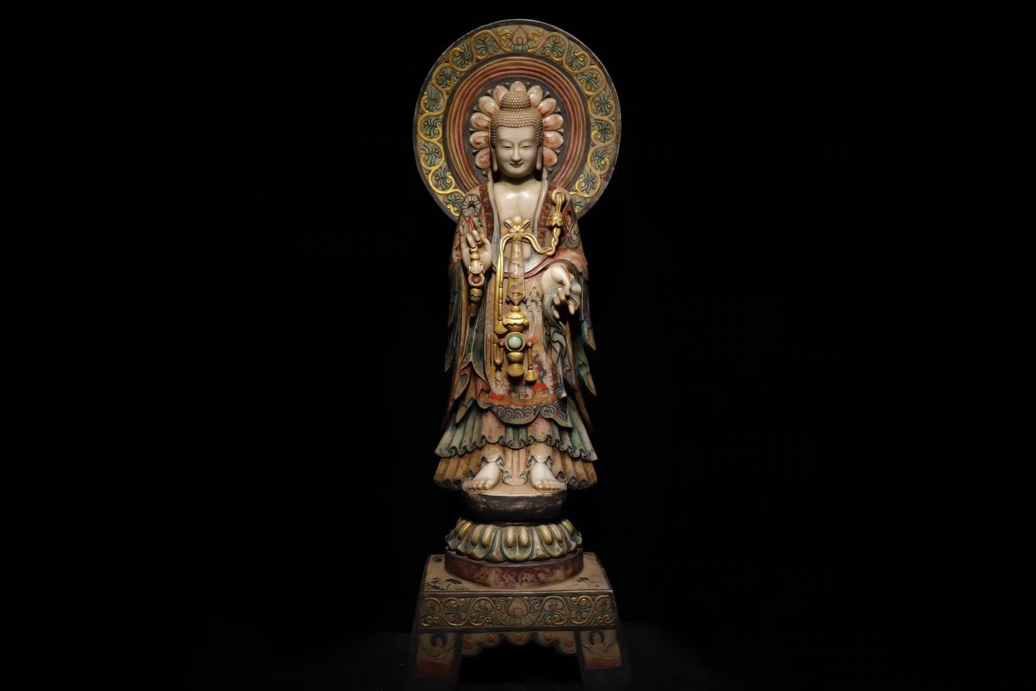 A full-body view of an ornate Kuan Yin statue with intricate robes and a detailed halo. She's standing in a gesture of compassion against a black background. This statue symbolizes serenity, wisdom, and spiritual presence.