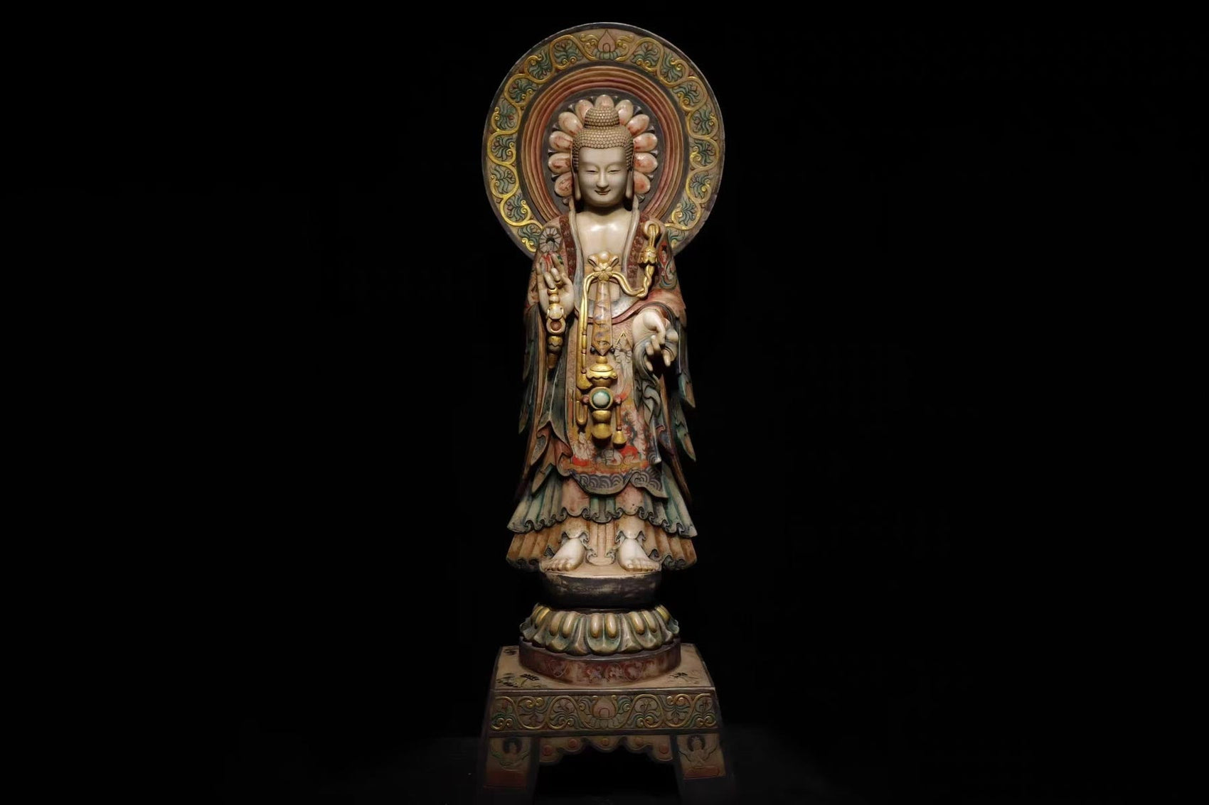 A full-body view of an ornate Kuan Yin statue with intricate robes and a detailed halo. She's standing in a gesture of compassion against a black background. This statue symbolizes serenity, wisdom, and spiritual presence.