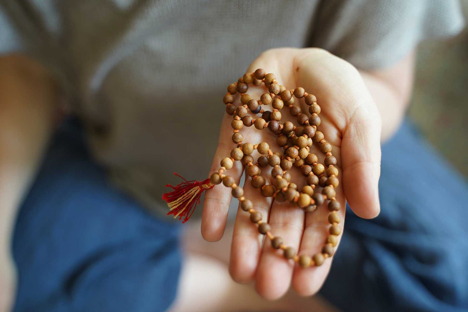 A woman gently holding mala beads in her hand - Mantrapiece.com