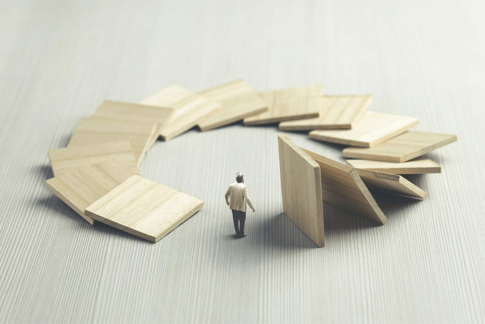 A man stands at the center of a circular domino effect, symbolizing how actions set in motion eventually return—illustrating the karmic cycle of cause and effect - Mantrapiece.com