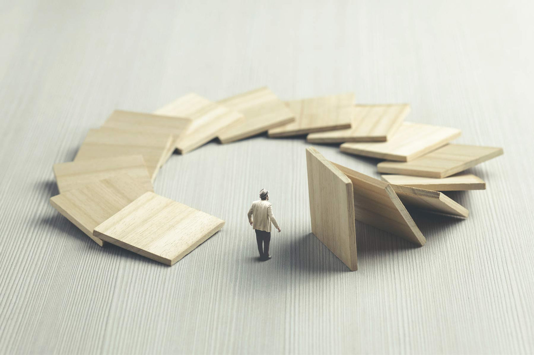 A man stands at the center of a circular domino effect, symbolizing how actions set in motion eventually return—illustrating the karmic cycle of cause and effect - Mantrapiece.com