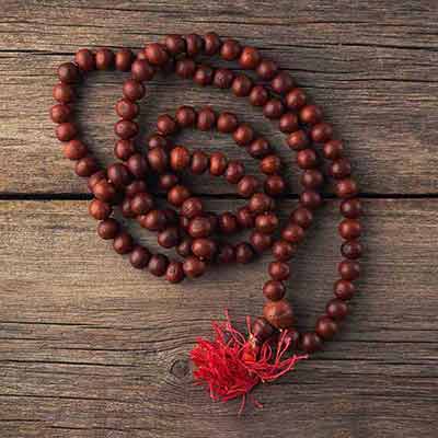 Wooden mala beads with a red tassel on a wooden surface