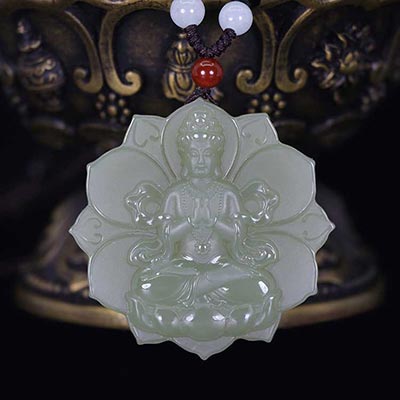 Green jade pendant with Buddha figure on a dark background