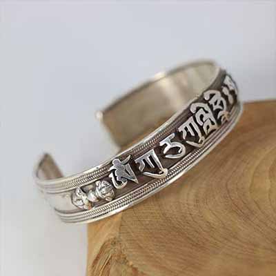 Silver bracelet with engraved design on a wooden block